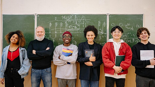 Gruppe Menschen lachend vor Schultafel